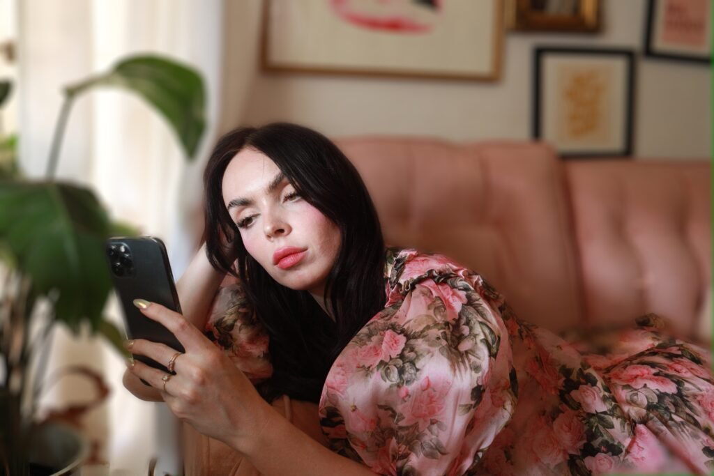 a woman laying on a couch looking at a cell phone